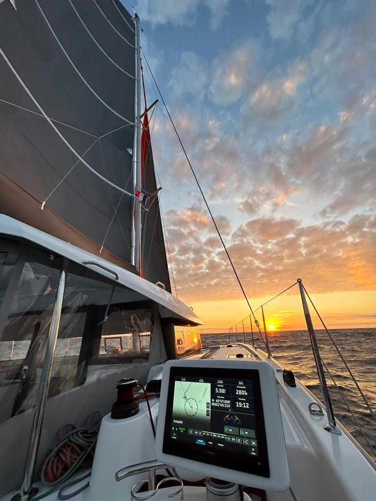 A yacht sailing towards the sunset on a yacht delivery