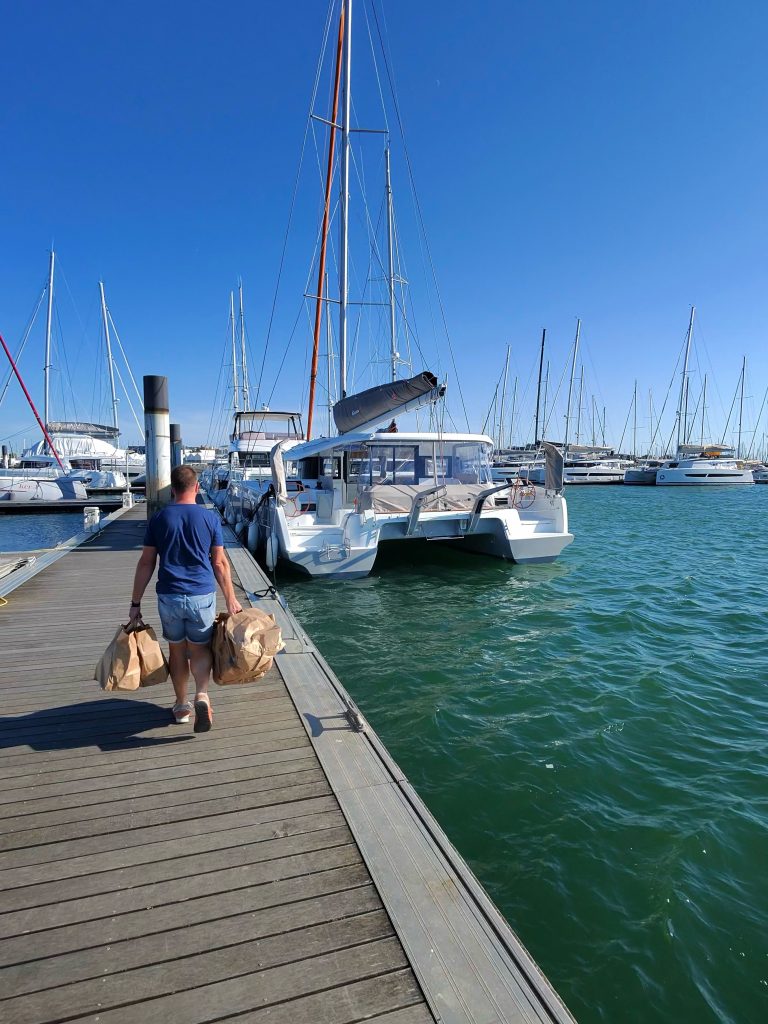 a skipper taking food to a large catamaran for delivery